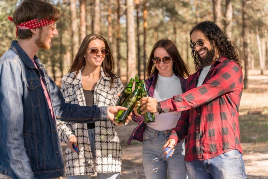Happy group of friends toasting craft beer bottles, capturing the social fun of a Denver RiNo Beer and Art tour experience.