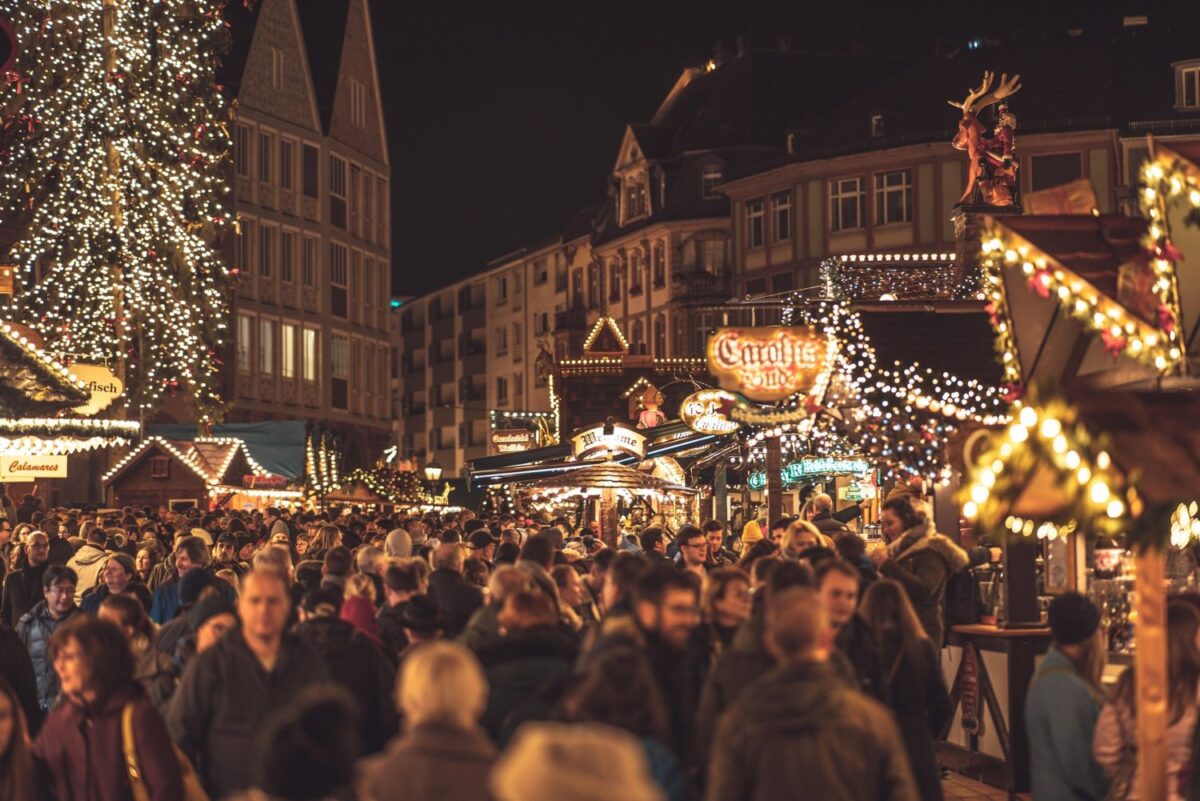 Crowds gather in a festive, brightly lit European-style winter market. Denver winter festivals